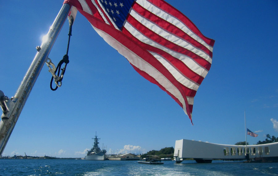 United States of America flag flying above the USS Arizona Memorial in Pearl Harbor on the island of Oahu. Photo credit ShutterStock.com, licensed.