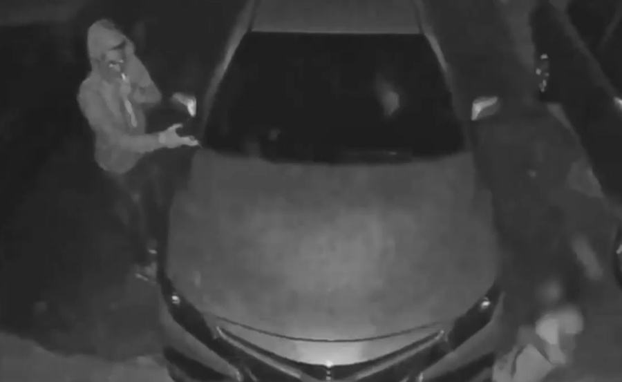 In the video, surveillance cameras captured video of one of the armed robbers just after 3 a.m. on April 7 walking toward the front of a car and pointing a gun, while the victim of the shooting, suffering from a gunshot wound, is lying on the ground, scooting around the front of the car.