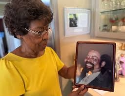 Photo of Daisy Marshall holding a framed picture of her late husband